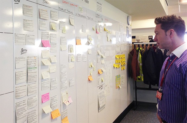 A man looking at sticky notes on a board. 