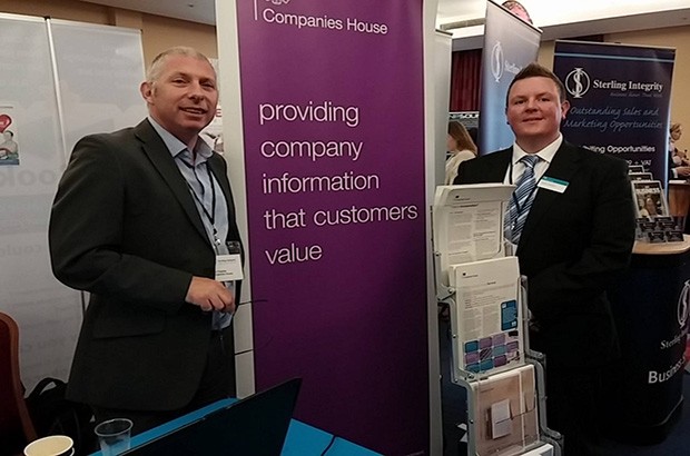 2 Companies House employees at the event, in front of a sign displaying 'Providing company information that customers value'. 