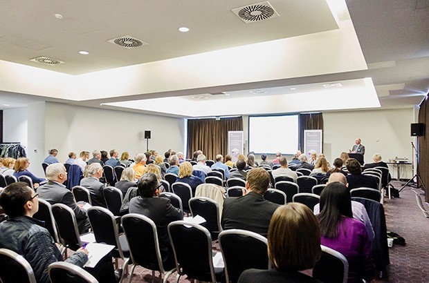 A conference hall filled with people on seats. 