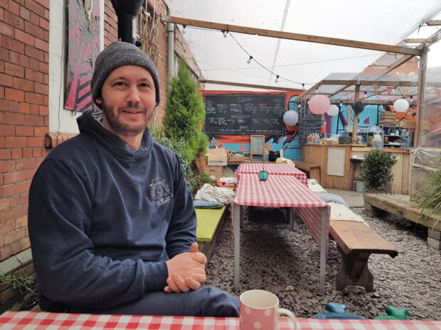 The co-founder of Dusty Knuckle Pizza, Phil Lewis, smiling at the camera in his restaurant. 