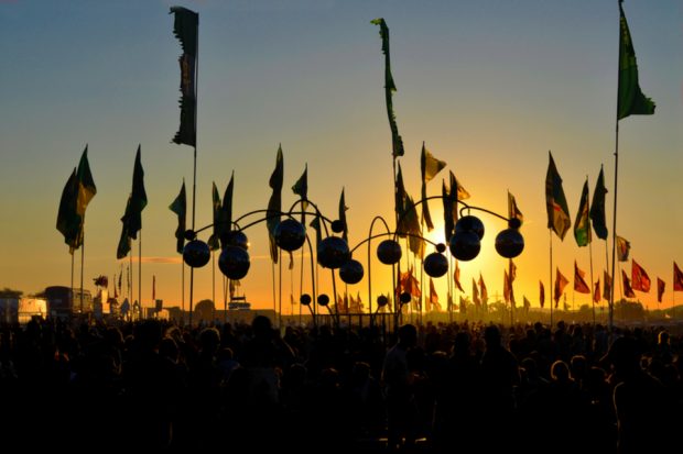 Sunset at Glastonbury with the crowd holding flags