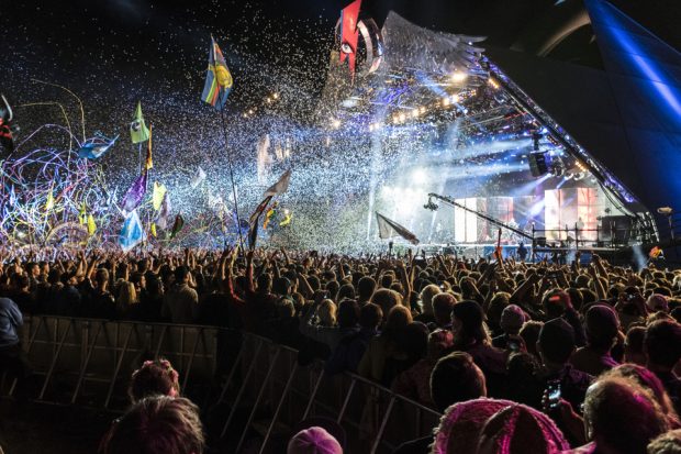 Glastonbury Festival Pyramid Stage at night during a concert with ticker tape floating down on the crowd