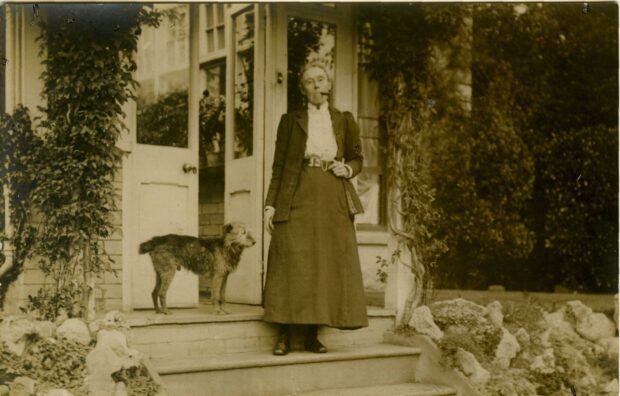 Amy Dillwyn standing outside her home on a step with a dog. 