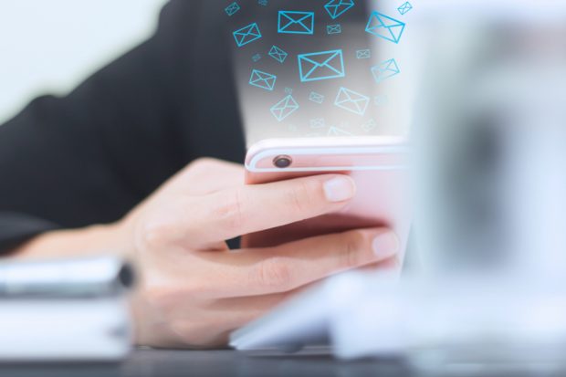 A hand holding a smart phone with email notifications. 