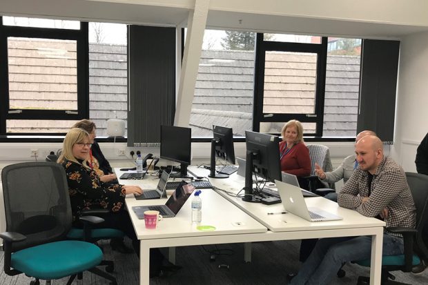 A group of people sat at desks with laptops. 