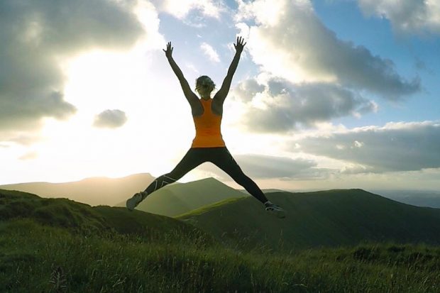 Sarah star jump on mountain summit.