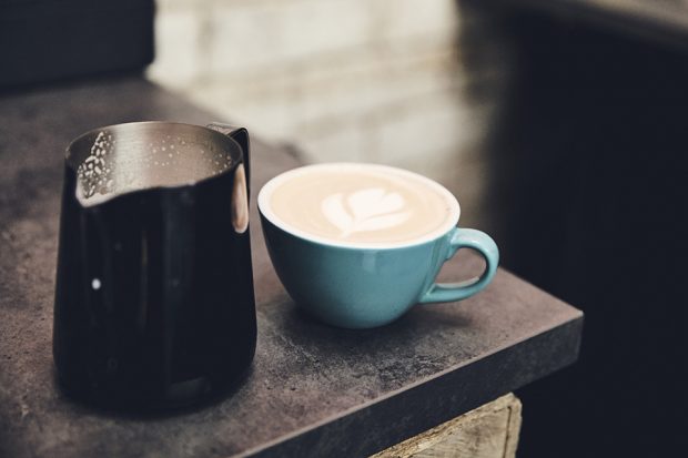 A cup of coffee and jug of milk.