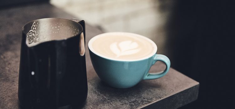 A cup of coffee and jug of milk.