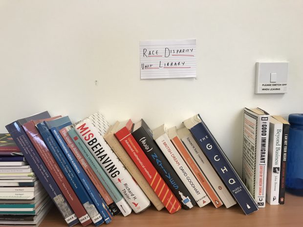 A library displaying lots of books with a sign above them reading 'Race Disparity Unit Library'. 