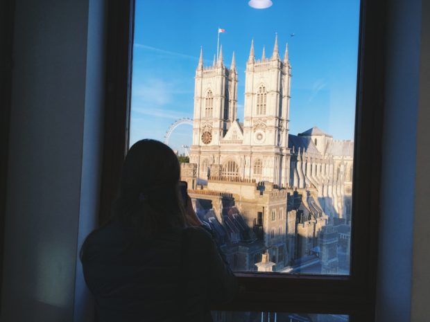 A person's silhouette taking a photo of Westminster Abbey, through a window.