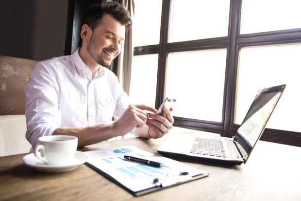 Man completing application with a laptop and a mobile phone.