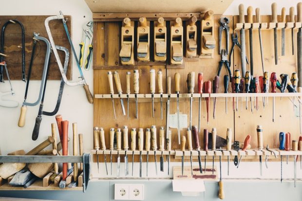 A wall displaying tools such as saws, screwdrivers and hammers. 