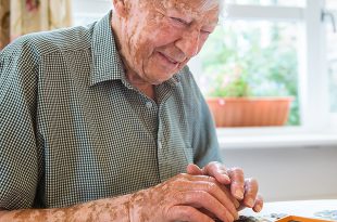 A smiling elderly man completing a puzzle.