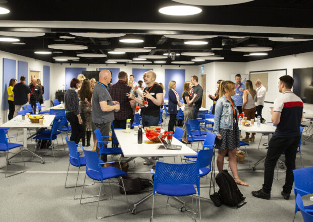 Attendees discussing ideas at the unconference - in a room full of tables and chairs. 