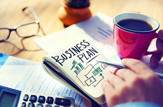 Close up of a desk showing a person writing a business plan.