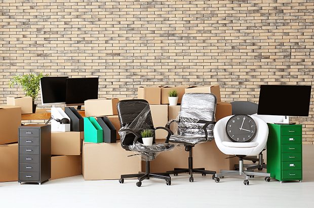 An pile of boxes and office furniture in an otherwise empty room
