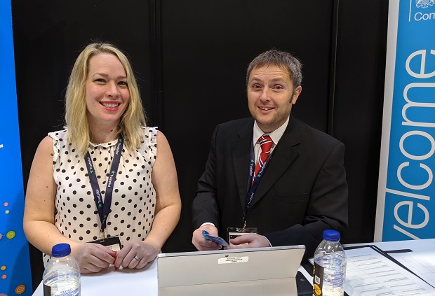 Smiling male and female employees sat behind a desk