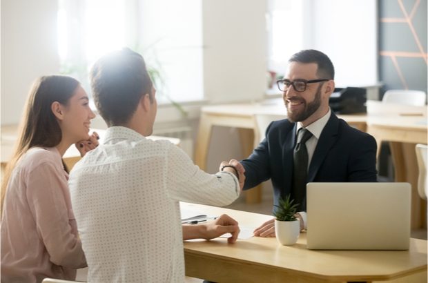 A legal representative shaking hands with a young couple