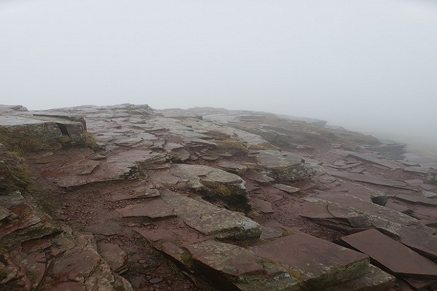 A rocky hilltop almost covered by mist. 