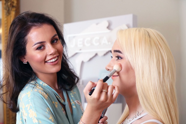 A photo of a lady doing another lady's make up.