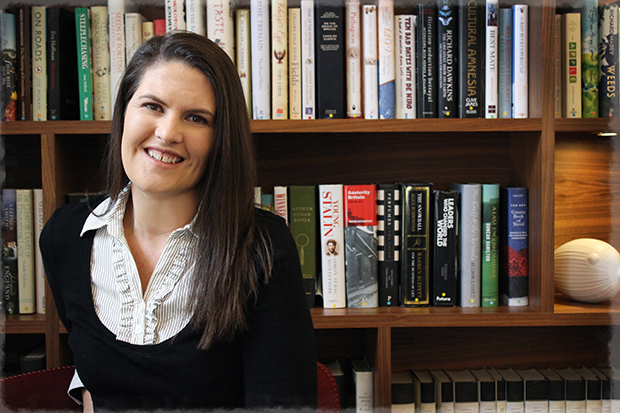 A person standing in front of a full book case and smiling at the camera.