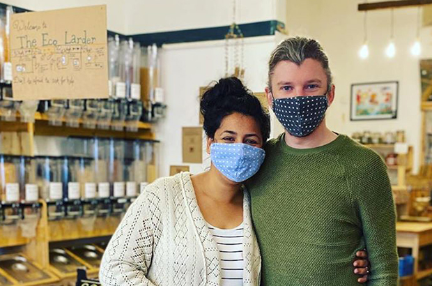 A couple standing in a shop wearing face coverings.