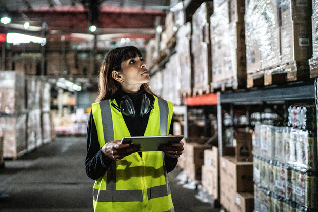 An employee wearing a high-vis jacket working in a warehouse. 