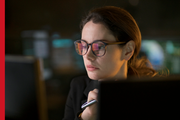 A woman wearing glasses looks at a computer screen
