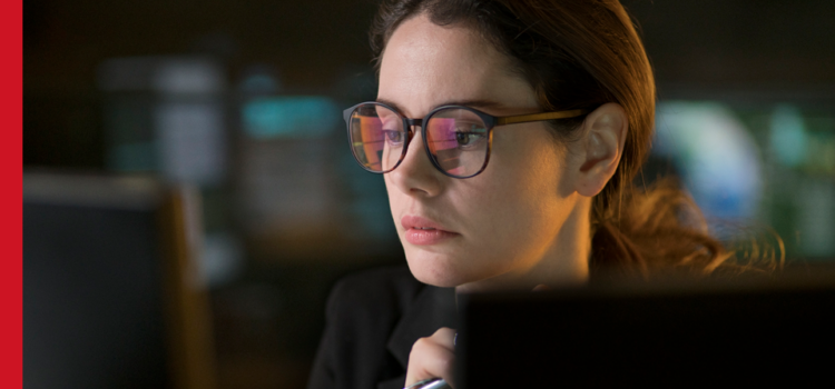 A woman wearing glasses looks at a computer screen