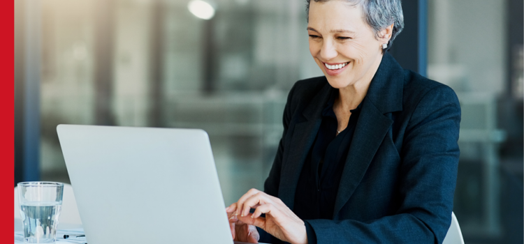 A formally dressed woman smiles as she types on a laptop