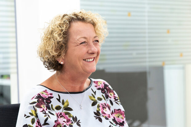 Louise Smyth, smiling. Louise is wearing a floral blouse within an office setting.