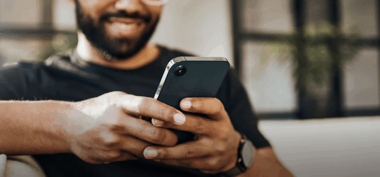 A man smiles whilst looking at his mobile phone