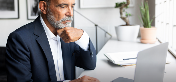 A man wearing a suit types on a laptop in a professional office setting