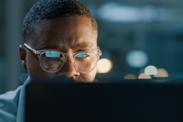 A man wearing glasses looks at a computer screen