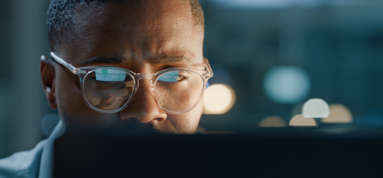 A man wearing glasses looks at a computer screen
